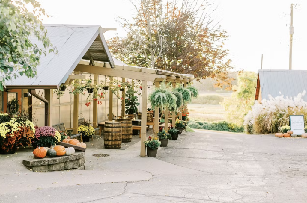 The outdoor garden area at The Greenhouse At Bittersweet with a tall wooden trellis, hanging plants, and tall barrels.